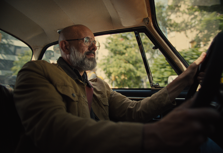 Distinguished older gentleman in a jacket, seated behind the wheel of a vehicle