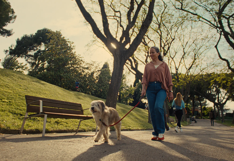 Active senior woman walking her dog in a vibrant park setting, promoting healthy aging